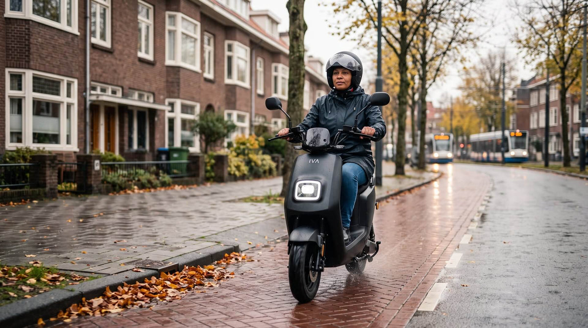 Elektrische scooter in de regen: vrouw rijdt op matzwarte IVA E-GO S4 2.0 over een nat wegdek in een Nederlandse stadsstraat
